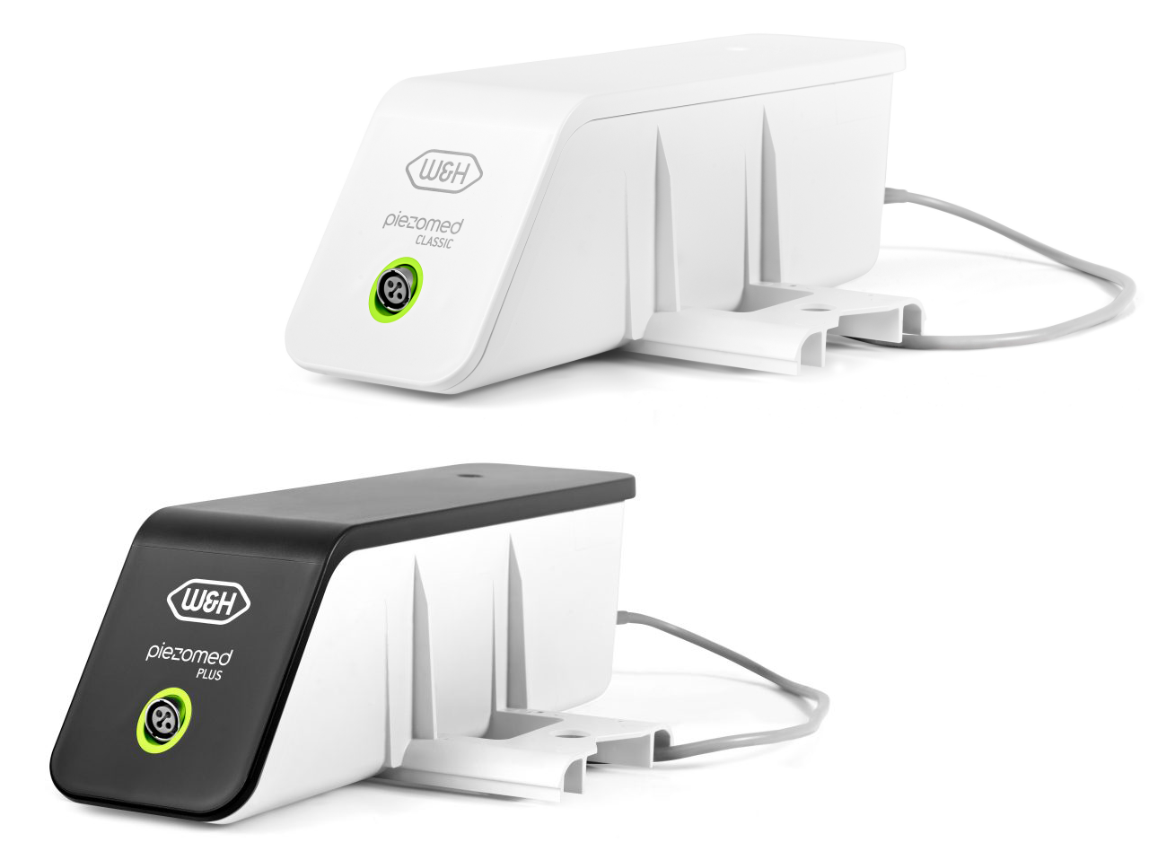 Image showing two W&H piezosurgery units used in dental implantology and bone surgery. The white device labeled "Piezomed Classic" and the black-top device labeled "Piezomed Plus" are compact units designed to power piezosurgical handpieces for precise, minimally invasive bone cutting with high safety and control.